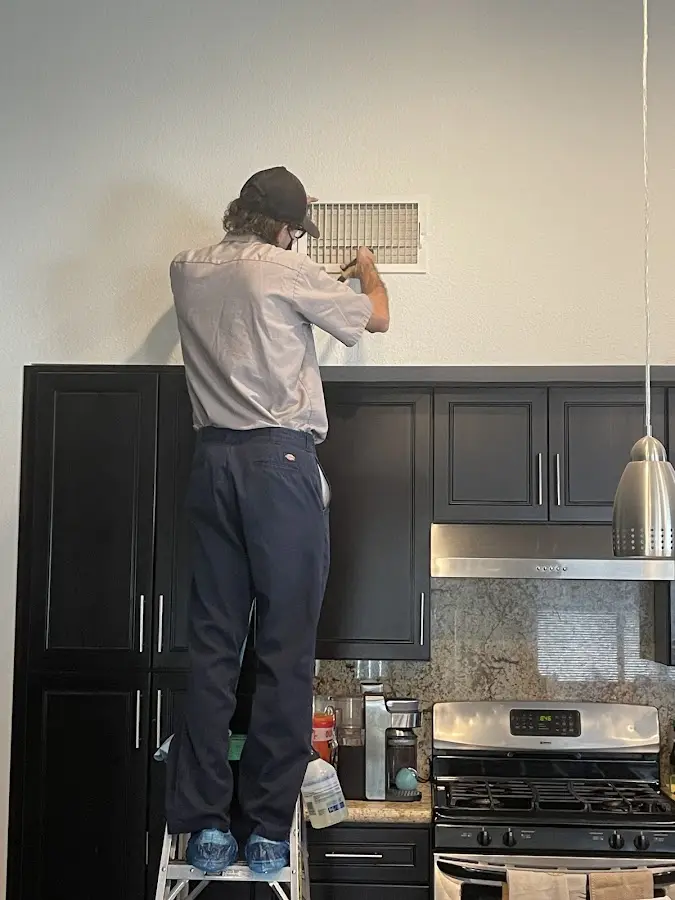 Technician inspecting an air vent during HVAC service in Athens